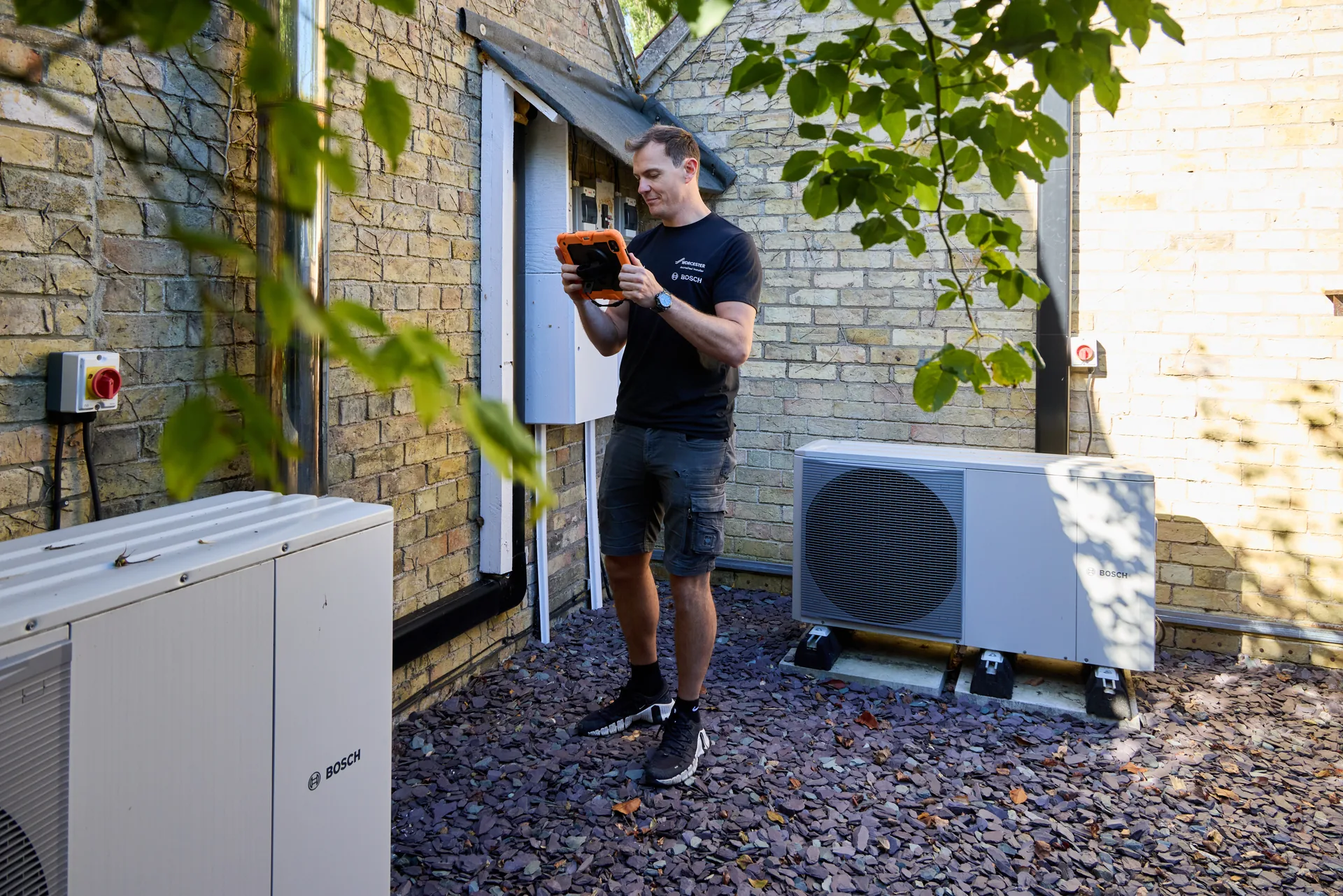 Liam using his iPad beside two Bosch heat pumps